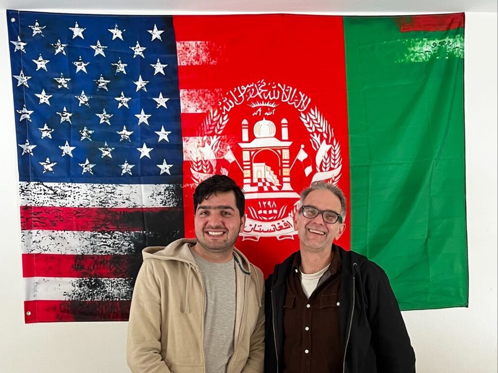Jan and Glen Robertson standing in front of a combination American-Afghan flag